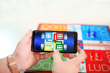 Family is playing ludo game in phone. Picture of ludo board game on the table.の写真素材