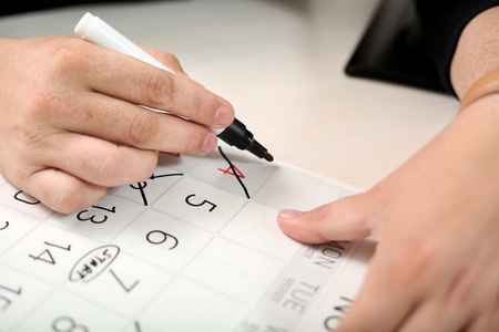 Hand is marking cross days off the black marker in the calendar.の写真素材