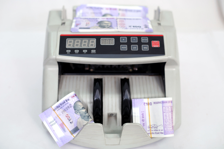 Money counting machine with new 100 rupees notes. Isolated on the white background.の写真素材