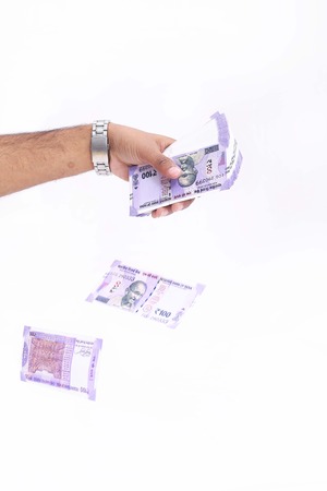 Man hand is throwing new Indian currency. Isolated on the white background.