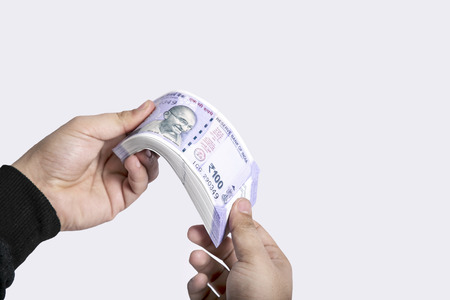 Picture of hand is holding Indian 100 rupee currency. Isolated on the white background.