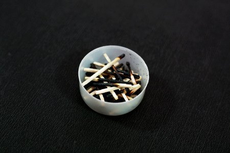 Picture of burned matchstick in the small pot. Isolated on the black background.の写真素材