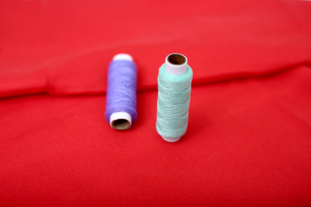 Picture of sewing thread on the red cloth.