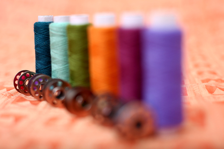 Spool of sewing thread with bobbin on the orange cloth.の写真素材