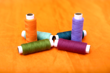 Picture of multicolored sewing thread. Isolated on the yellow background.