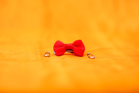 Picture of safety pin and red bow. Isolated on the yellow background.
