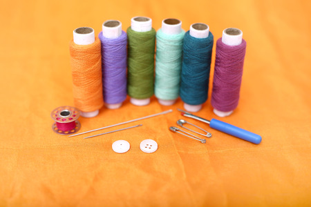 Picture of multicolored sewing thread, needle, bobbin, button, safety pin and needle ripper....