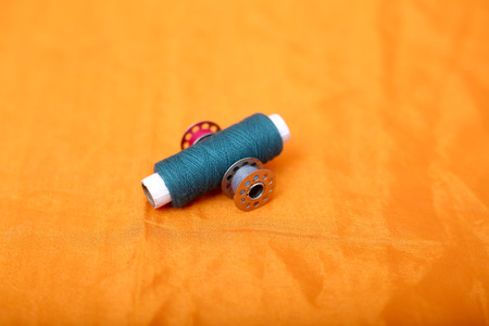 Picture of blue sewing thread and bobbins. Isolated on the yellow background.