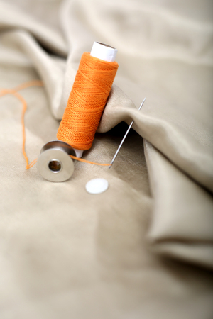 Portrait of needle attached in cloth with Orange Sewing thread and bobbin.の写真素材