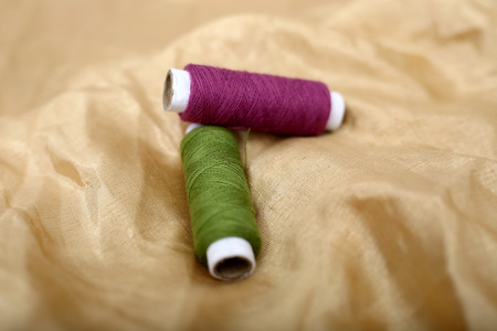 Picture of two sewing thread on the golden cloth.