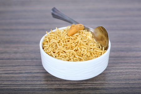 Namkeen bikaneri bhujia in the bowl with spoon. Isolated on the wooden background.の写真素材
