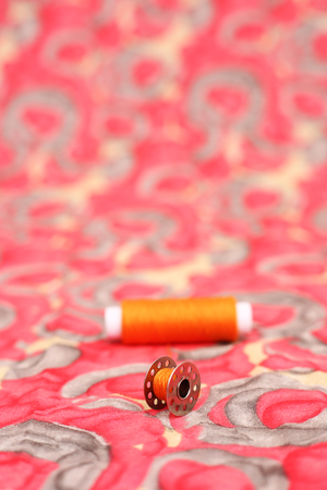 Portrait of orange thread with bobbin. Isolated on the colorful background.の写真素材