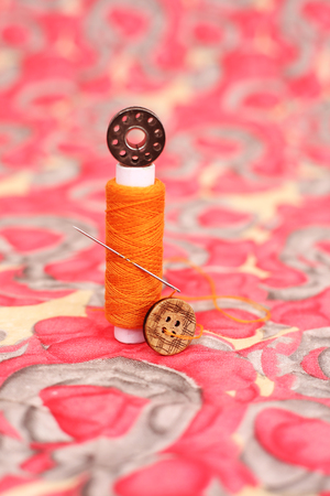 Picture of sewing thread, bobbin and button. Isolated on the colorful background.の写真素材