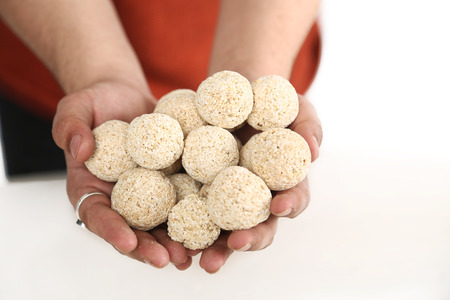 Picture of man hand is holding many cholai ke ladoo. Isolated on the white background.の写真素材