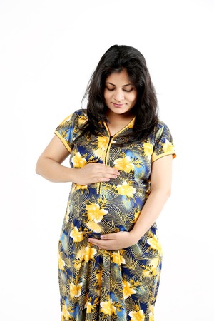 Beautiful pregnant woman is touching belly. Isolated on the white background.の写真素材