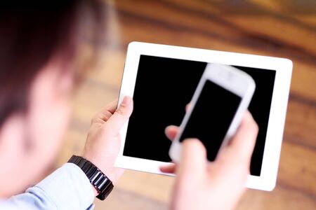 Man working on mobile and holding tablet in hand. Isolated on white background.