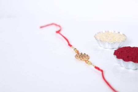 Indian festival: Raksha Bandhan background with an elegant Rakhi, Rice Grains and Kumkum. A...