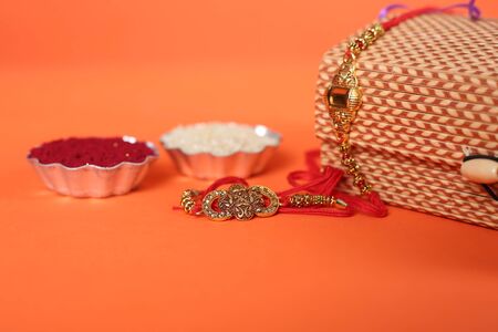 Indian festival: Raksha Bandhan background with an elegant Rakhi, Rice Grains and Kumkum. A...