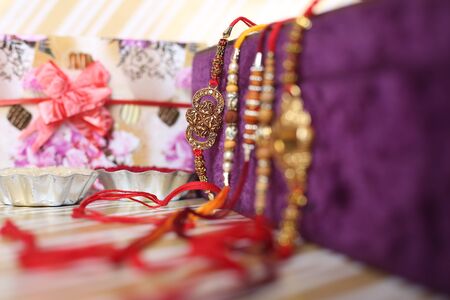 Indian festival: Raksha Bandhan background with an elegant Rakhi, Rice Grains and Kumkum. A...