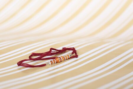 Indian festival: Raksha Bandhan background with an elegant Rakhi, Rice Grains and Kumkum. A traditional Indian wrist band which is a symbol of love between Brothers and Sisters.の写真素材