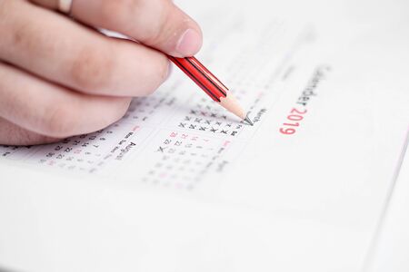 Picture of Man holding Calendar and marking on date. Isolated on white background.の写真素材