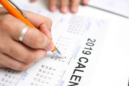 Picture of Man holding Calendar and marking on date. Isolated on white background.の写真素材