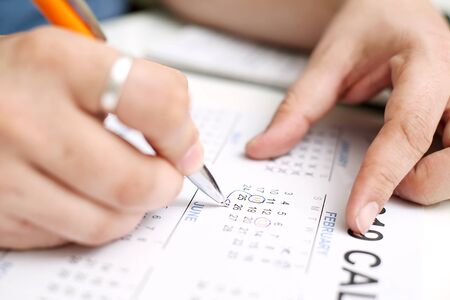 Picture of Man holding Calendar and marking on date. Isolated on white background.の写真素材