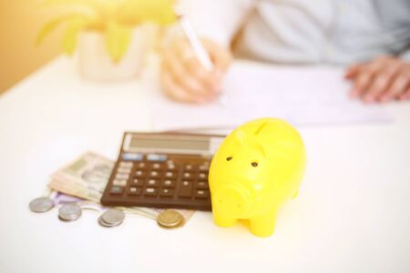 Picture of person depositing money in a yellow piggy bank. Isolated on background.の写真素材