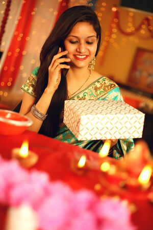 Portrait of a beautiful young Indian woman in traditional dress celebrating diwali festival with in decorative background on the occasion of Diwali, Studio portrait.の写真素材