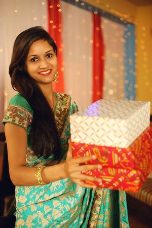Portrait of a beautiful young Indian woman in traditional dress celebrating diwali festival with in decorative background on the occasion of Diwali, Studio portrait.の写真素材