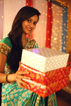 Portrait of a beautiful young Indian woman in traditional dress celebrating diwali festival with in decorative background on the occasion of Diwali, Studio portrait.の写真素材