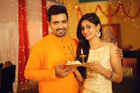 Indian couple is Celebrating Diwali. Isolated on decorative background.の写真素材