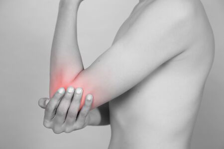 Man feeling a pain in his elbow on grey backgroundの写真素材