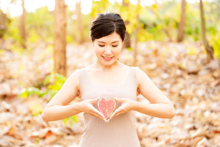 A woman with a red heart mark in natureの写真素材
