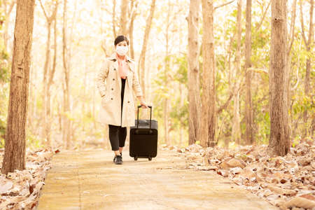 a woman in a mask with a black travel suitcaseの写真素材