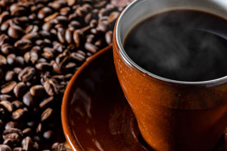 Hot coffee in a cup and coffee beans in the backgroundの写真素材