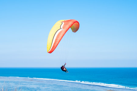 Colorful paraglider flying in the blue skyの写真素材