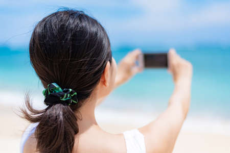 A woman in the sea with a smartphoneの写真素材