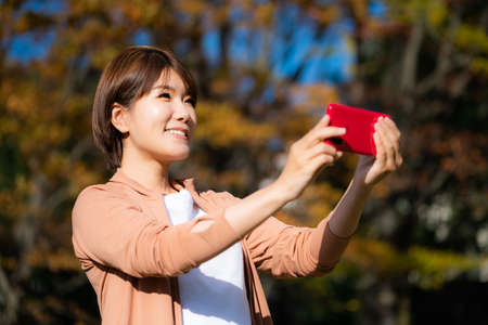 Woman holding smartphone in autumn scenery