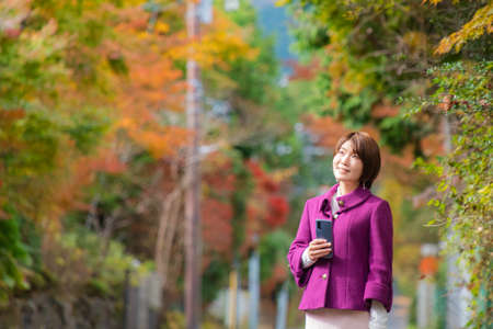 Woman with smartphone in autumn landscapeの写真素材