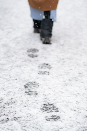 Woman's feet walking on snowy roadの写真素材
