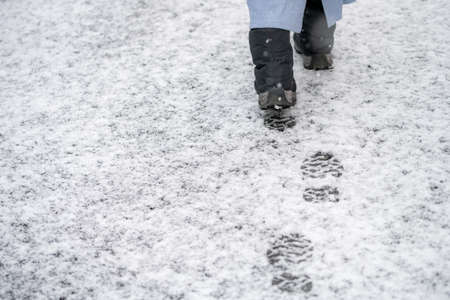 Woman's feet walking on snowy roadの写真素材