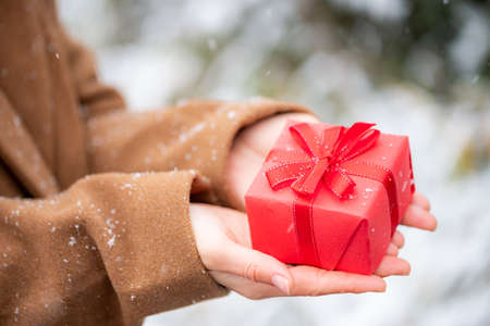 Close-up of person holding box of red presents outdoors in winterの写真素材