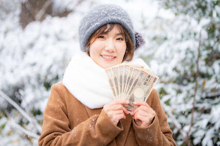 Woman holding cash in hand outdoors in winterの写真素材