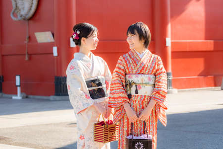 Two Japanese girls in kimono holding a gift box in front of the temple