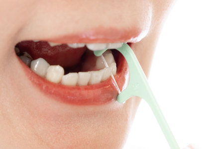 <p>Close up of a young woman brushing her teeth with dental floss</p>の写真素材