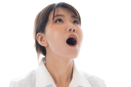 young asian businesswoman shouting and looking up isolated on white backgroundの写真素材