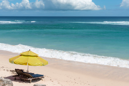 Beach chair and umbrella on the sandy beach with ocean in background