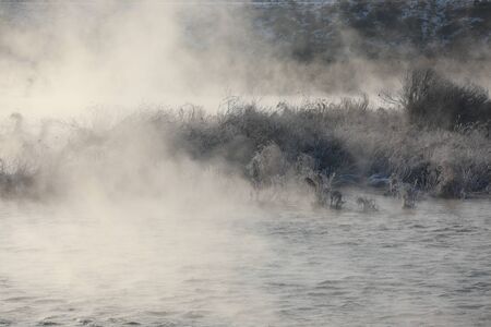 Trees and reeds are covered with snow, and the river has water mist. Soyang River, Chuncheon City, Koreaの写真素材