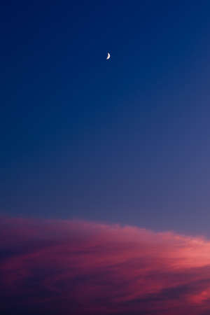 Night sky sunset time, beautiful red clouds and moon landscape.の写真素材